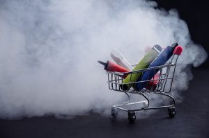 Portable vaporizers and vaporizer pens in a small shopping cart shrouded by a cloud of mist that forms at optimal cannabis vaporization temperatures
