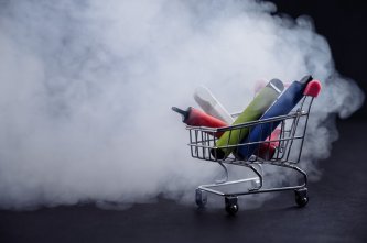 Prenosné vaporizéry a vaporizačné perá v malom nákupnom vozíku zahalené oblakom hmly, ktorý sa tvorí pri optimálnych teplotách vaporizácie konope