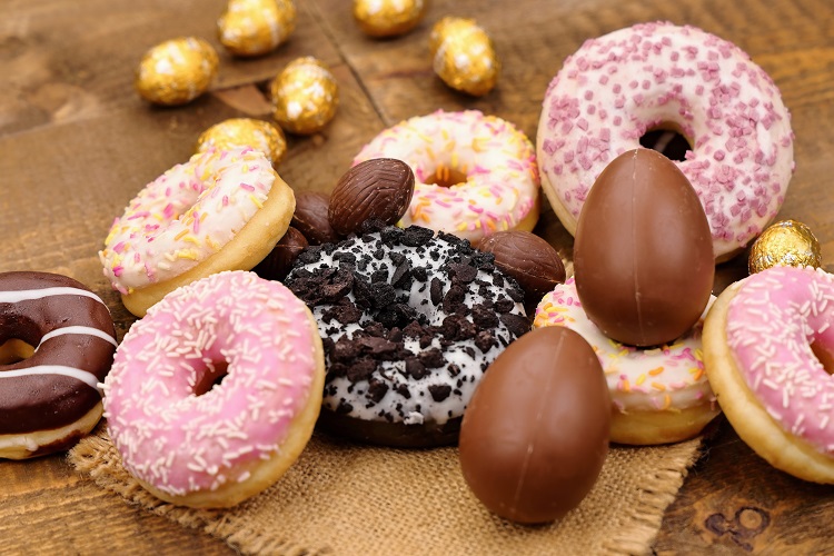 Colorful donuts with chocolate eggs on a wooden background, while sweets can alleviate unpleasant experiences at HHC