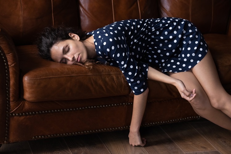 Sleeping young woman on the sofa with her eyes closed - dozing, daydreaming, tiredness and lack of energy